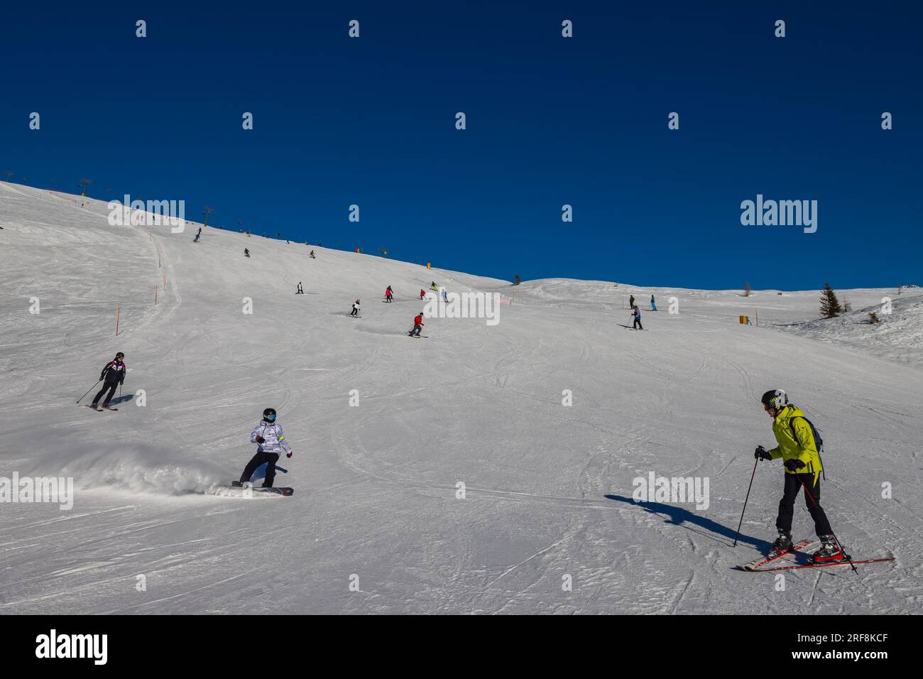 Falcade, Italie - 15 février 2023 : piste de ski avec skieur sous ciel bleu. Les gens descendent les montagnes enneigées à skis. Groupe de skieurs sur une piste de ski Banque D'Images