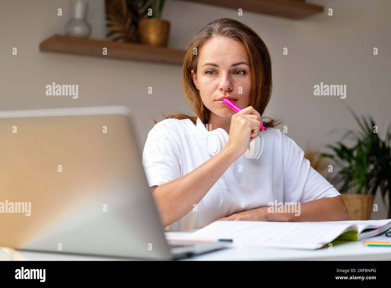 Jeune femme adulte faisant des devoirs de cours en ligne en utilisant het ordinateur portable et cahier de travail, éducation à distance de la maison. Banque D'Images