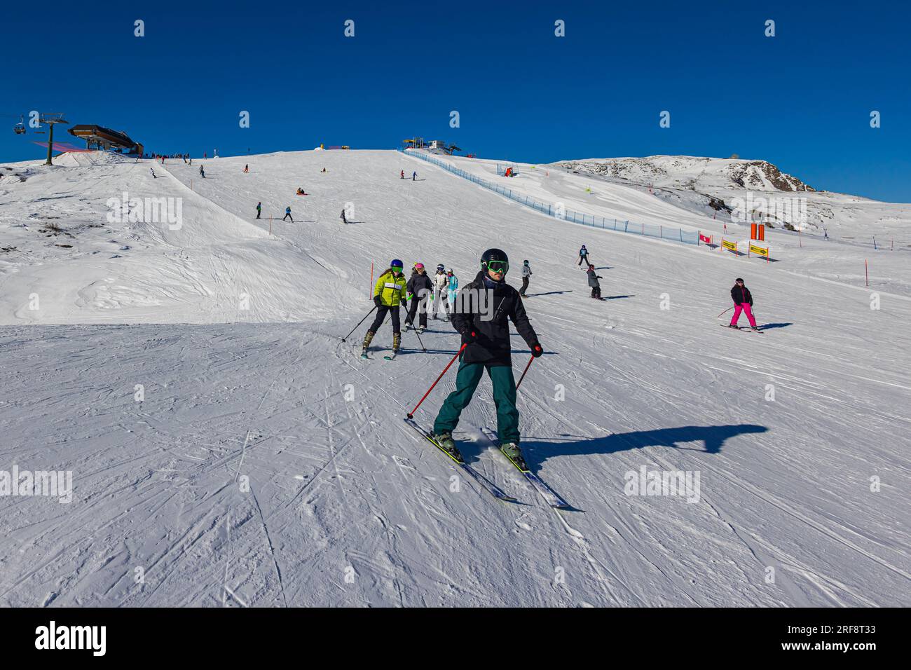 Falcade, Italie - 15 février 2023 : piste de ski avec skieur sous ciel bleu. Les gens descendent les montagnes enneigées à skis. Groupe de skieurs sur une piste de ski Banque D'Images