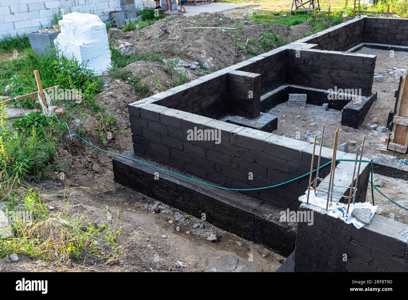 Semelles en blocs de béton peintes avec masse asphalte-caoutchouc de dispersion noire, piliers en béton armé visibles. Banque D'Images