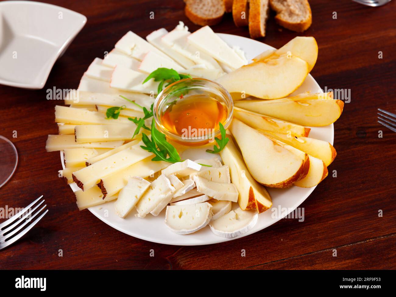 Assiette avec différents types de fromage et une tasse de miel Banque D'Images