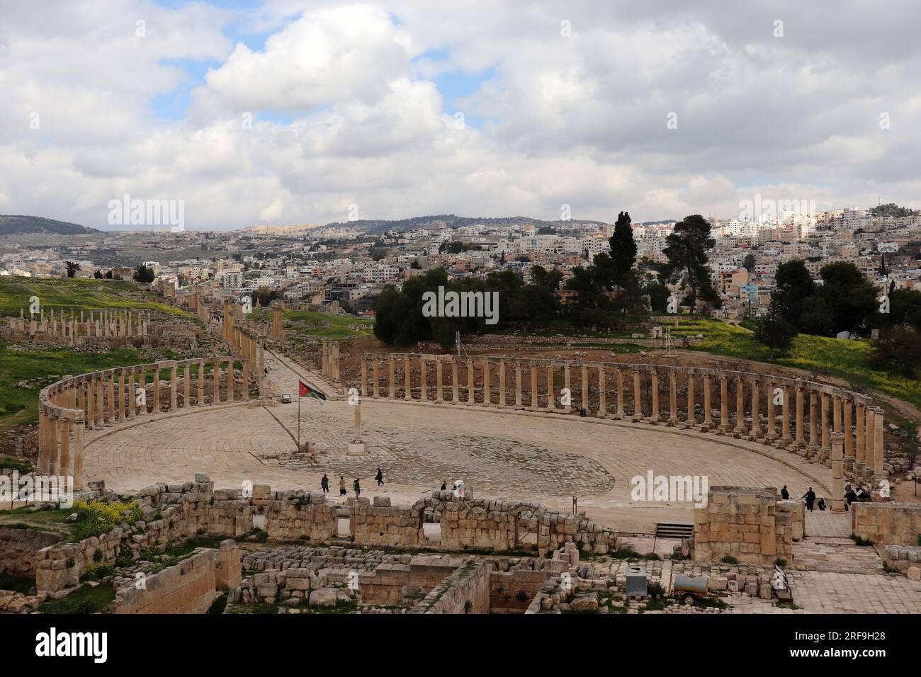 Colonnes du Forum ovale dans l'ancien Jerash, Jordanie (ville de Rome) et nouveaux bâtiments de Jordaniens / drapeau jordanien Banque D'Images