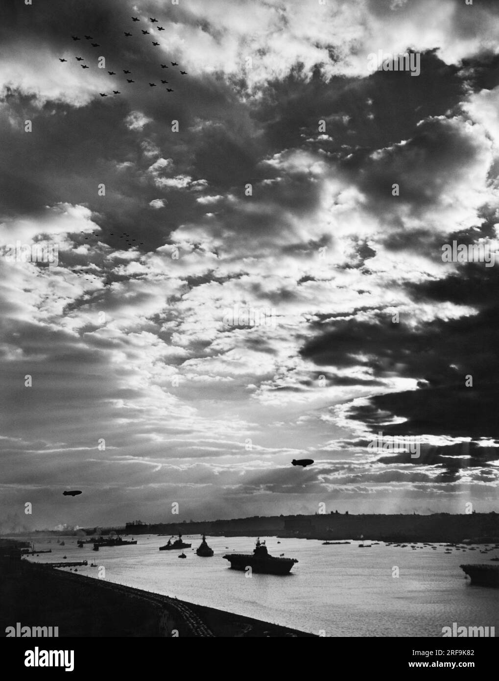 New York, New York : 29 octobre 1945 des escadrons d'avions volent au-dessus et des blimps pendent dans le ciel alors que la plus grande célébration de la Navy Day dans l'histoire de New York touche à sa fin. Le porte-avions USS Enterprise, le navire le plus décoré de l'histoire de l'US Navy, survole l'Hudson au premier plan. Banque D'Images