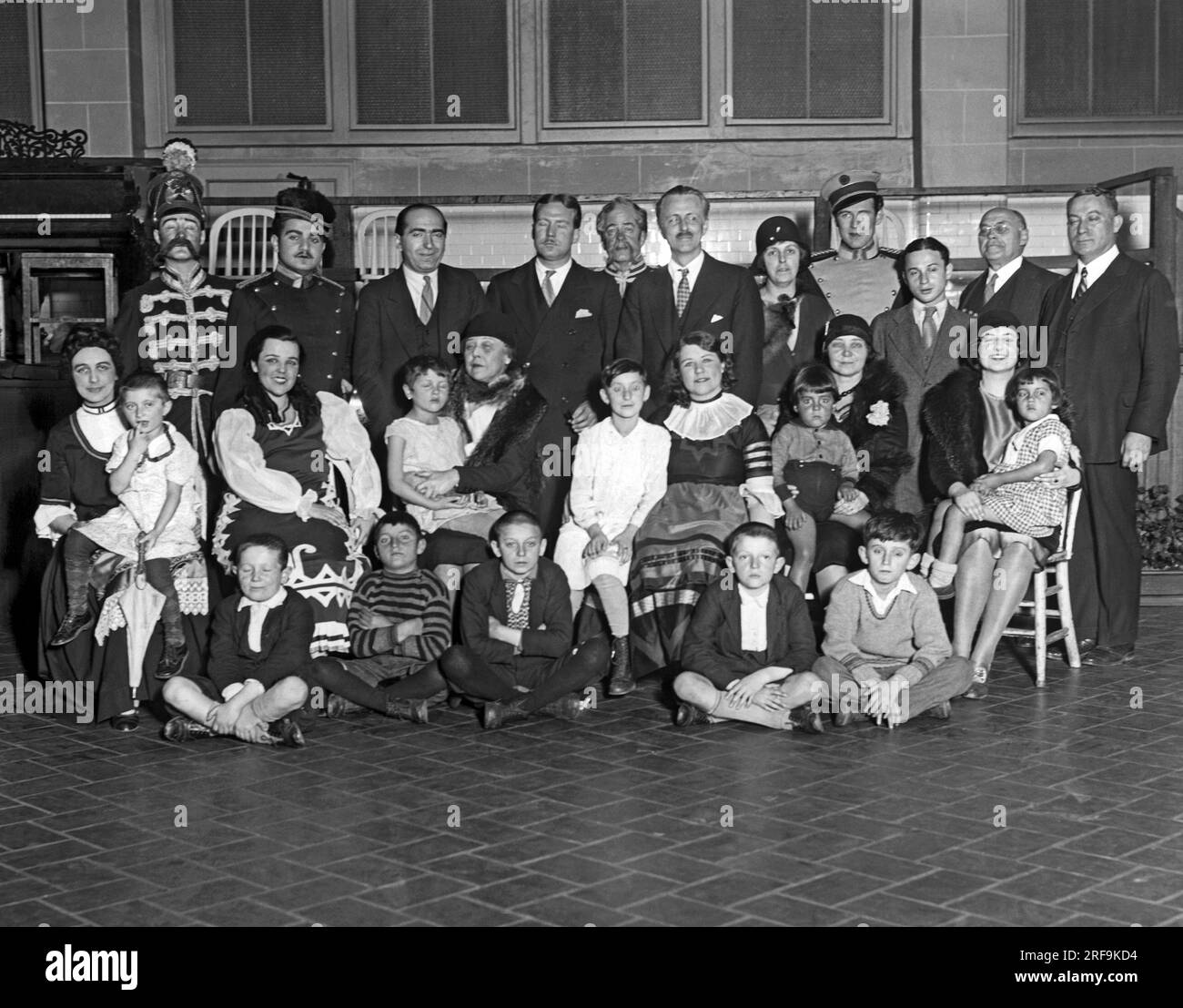 New York, New York : c. 1935. La Little Theater Opera Company visite Ellis Island pour y divertir les personnes détenues. La troupe est montrée dans une photographie qui comprend de nombreux immigrants, y compris des enfants roumains, italiens, yiddish, polonais et espagnols. Banque D'Images