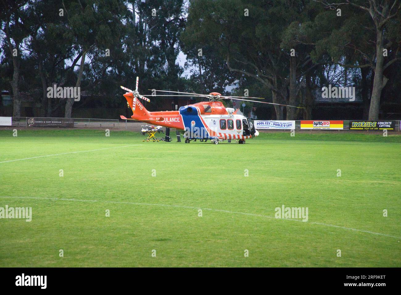 Une ambulance aérienne stationnaire Helicpoter Victoria Australie sur un terrain de football lumineux artificiellement éclairé dans une ville de campagne au coucher du soleil. Banque D'Images