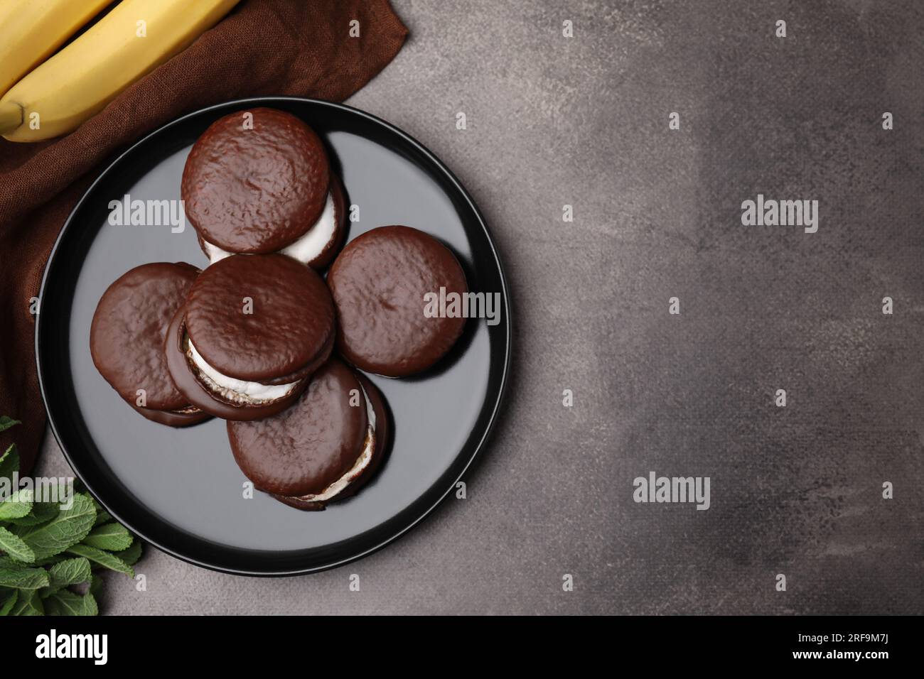 Savoureuse tartes au chocolat sucré, bananes et menthe sur la table brune, mise à plat. Espace pour le texte Banque D'Images