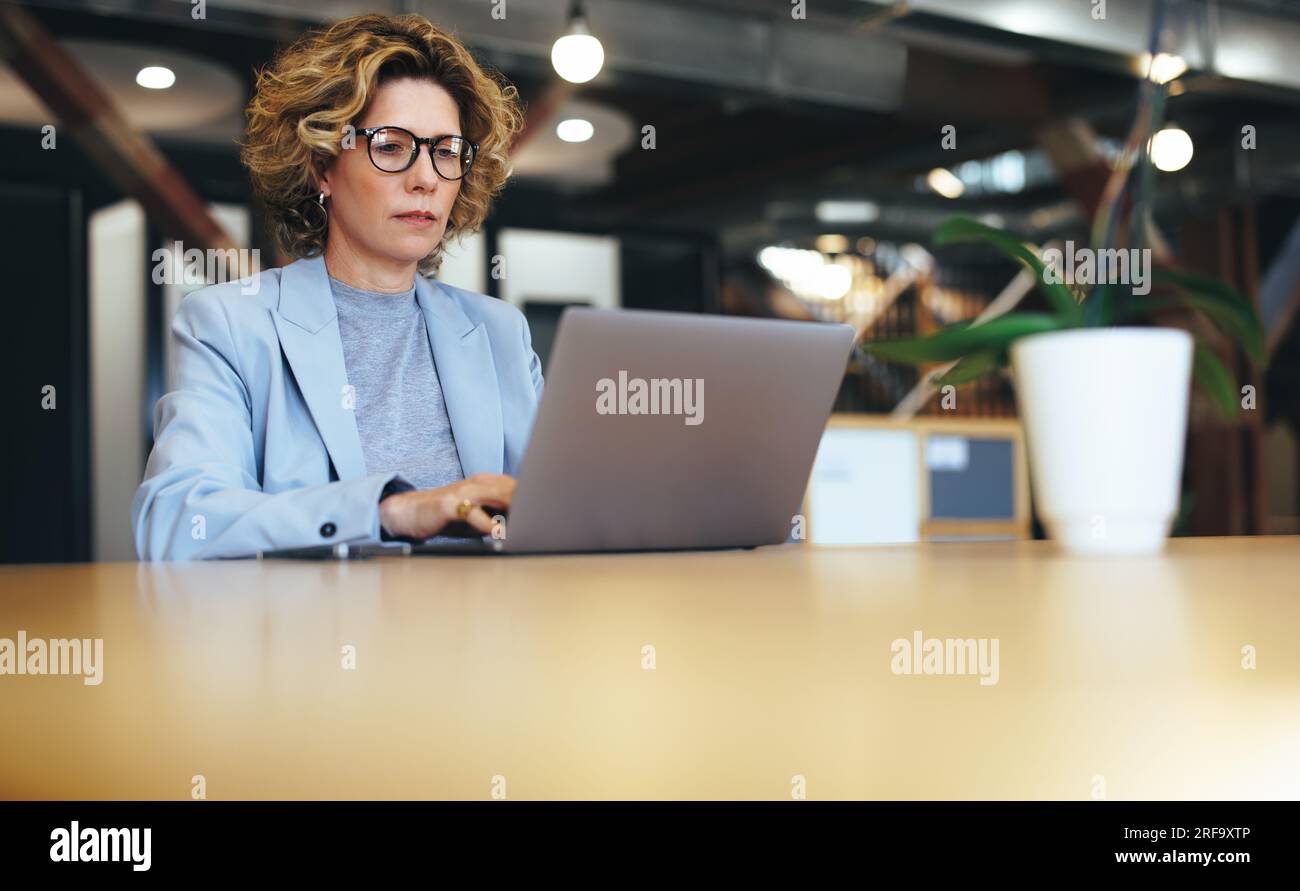 femme d'affaires travaillant sur un ordinateur portable dans un bureau de coworking. Femme d'affaires mature travaillant sur un projet en ligne. Professionnelle féminine travaillant à distance. Banque D'Images