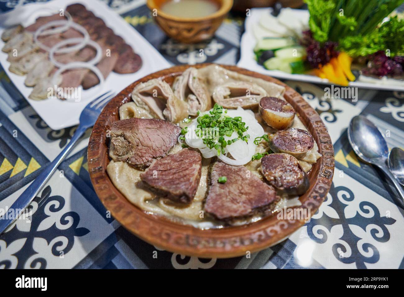 Plat traditionnel kazakh asiatique Beshbarmak : nouilles à l'agneau et aux oignons en gros plan sur une assiette sur la table. près du bouillon dans des bols. dastarkhan. boled Banque D'Images