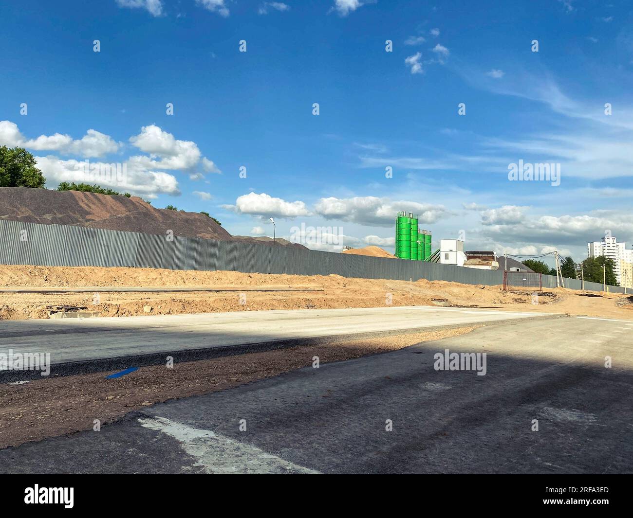 construction dans la ville. unité en béton cru pour la préparation de matériaux pour la fabrication de blocs de construction. derrière une haute clôture grise se trouve un tas de sable et de stons Banque D'Images