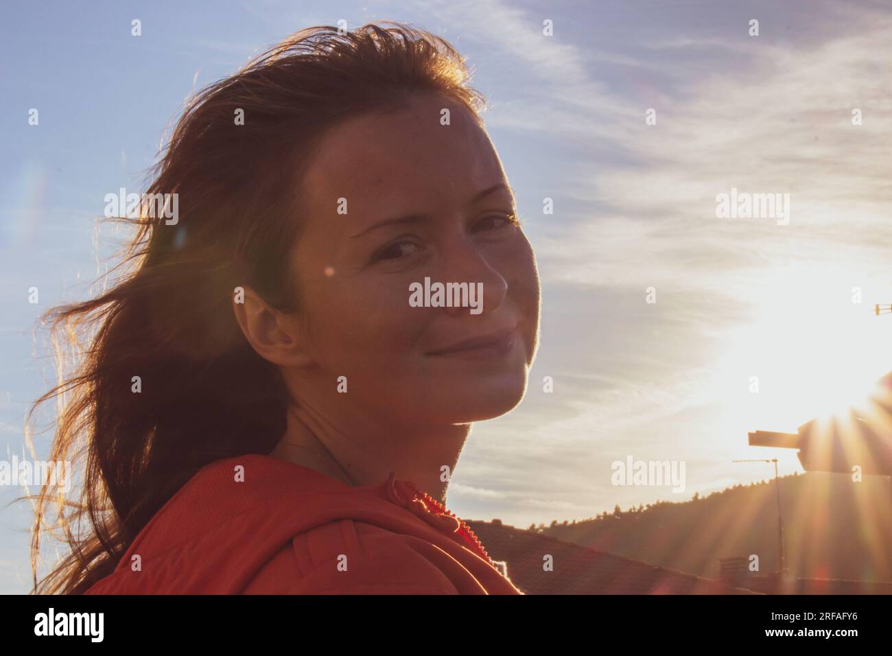 Fille souriante au soleil. Portrait de belle femme au coucher du soleil. Heureux touriste au crépuscule du soir. Joyeux pèlerin regardant la caméra. Modes de vie actifs. Banque D'Images