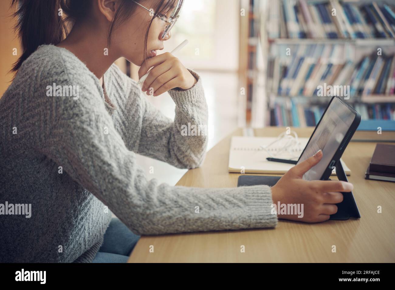 Femme étudiante asiatique lire des livres dans la bibliothèque à l'université. Jeune fille stress fatiguée ont problème tout en étudiant dur. Concept de tristesse Banque D'Images