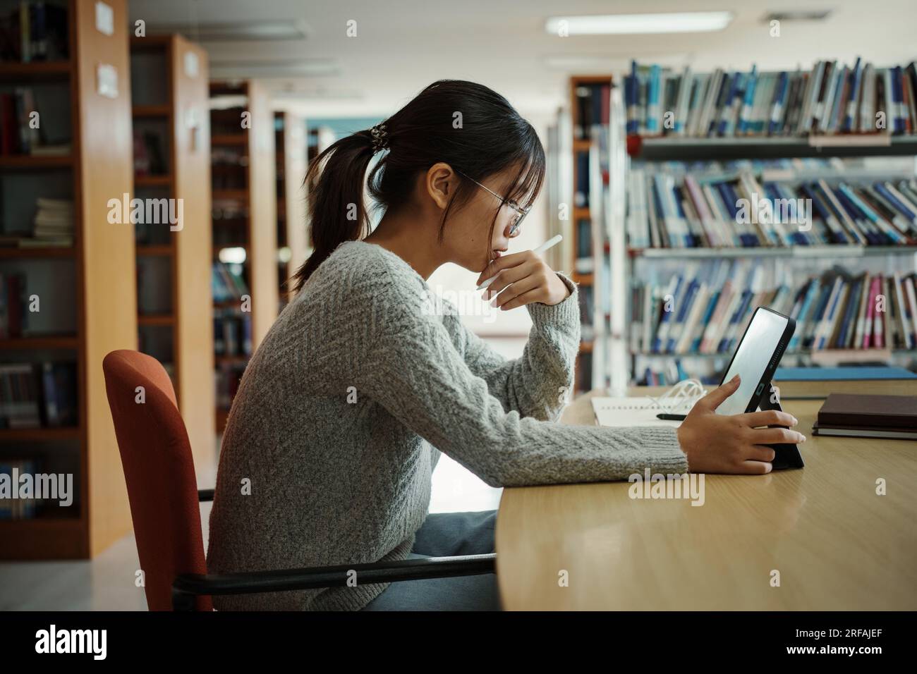Femme étudiante asiatique lire des livres dans la bibliothèque à l'université. Jeune fille stress fatiguée ont problème tout en étudiant dur. Concept de tristesse Banque D'Images