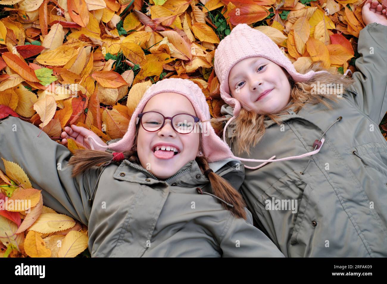 Portrait de deux mignonnes filles sœurs jumeaux couchées sur les feuilles au parc d'automne. Photo horizontale Banque D'Images
