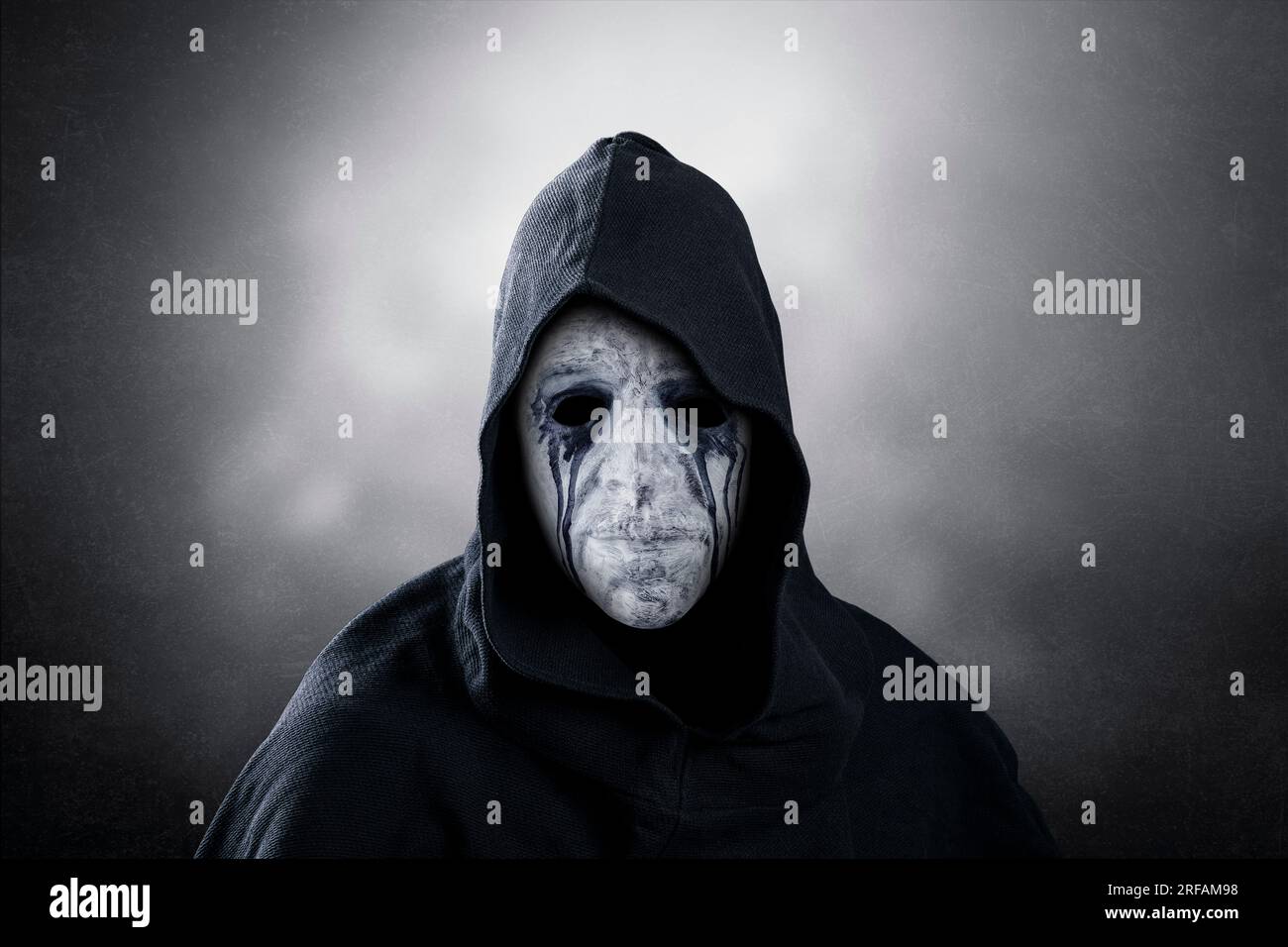 Figurine sinistre avec cape à capuchon sur fond sombre et brumeux Banque D'Images