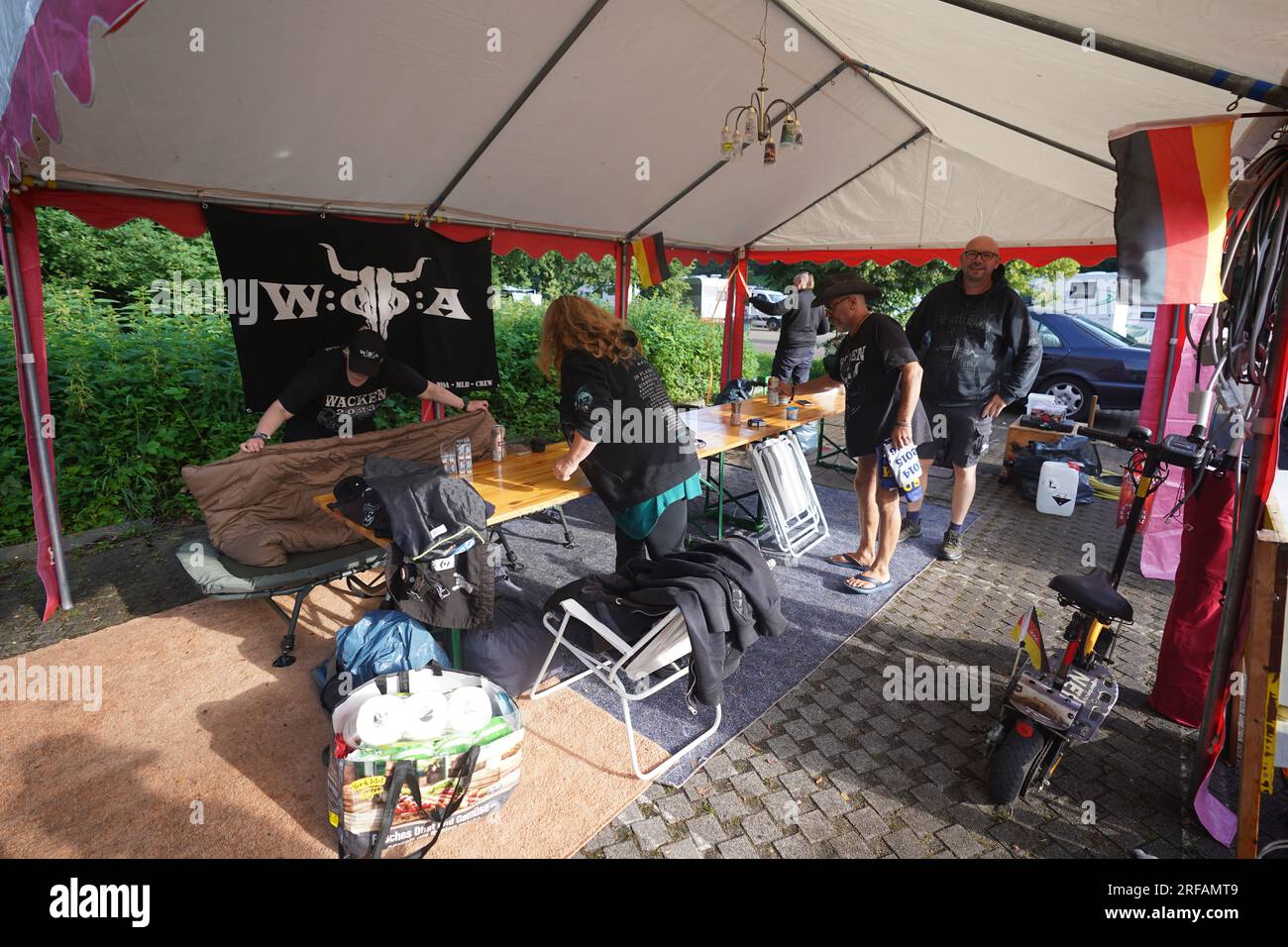 Hambourg, Allemagne. 02 août 2023. Les fans de Wacken de Lutherstadt Eisleben, qui ont dû passer la nuit sur le parking Rot au Volksparkstadion en raison de l'arrêt d'arrivée au Wacken Open Air (WOA), emballent à nouveau leur matériel de camping avant leur voyage de retour dans la matinée. La pluie continue a transformé la zone en champs de boue à l'avance, donc plus de véhicules ne devraient être sur le site pour le moment. Mercredi matin, les organisateurs ont annoncé que même les fans sans voitures ne seraient pas autorisés à arriver. Il y a peu d'espoir pour un meilleur temps. Crédit : Marcus Brandt/dpa/Alamy Live News Banque D'Images