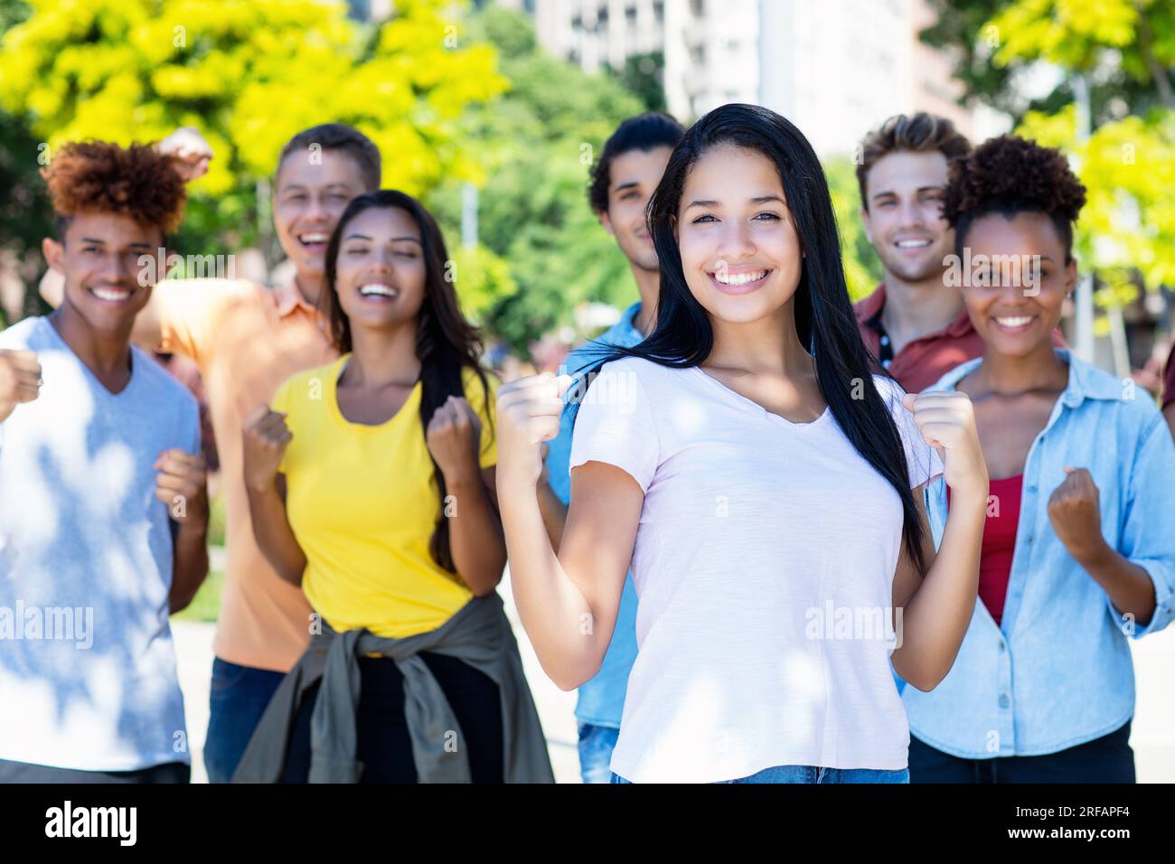 Belle étudiante sud-américaine avec groupe de jeunes adultes acclamés en plein air en été dans la ville Banque D'Images