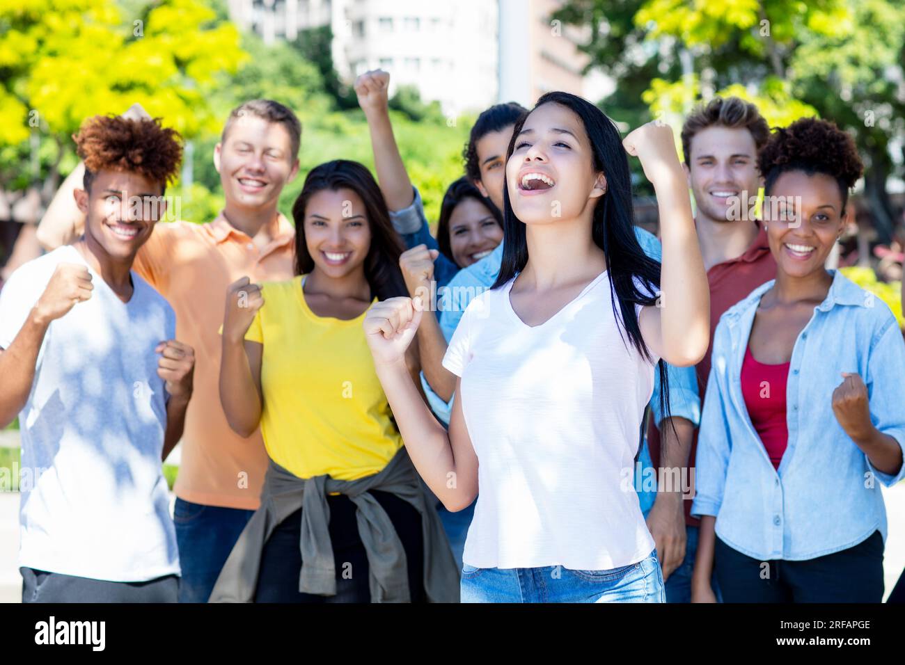 Étudiante sud-américaine réussie avec un groupe de jeunes adultes encourageants en plein air en été dans la ville Banque D'Images
