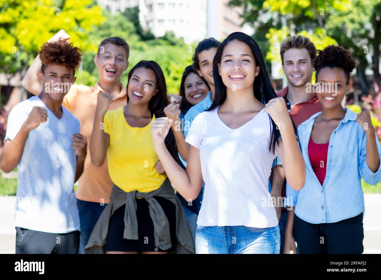Jeune étudiante sud-américaine avec groupe de jeunes adultes acclamés en plein air en été dans la ville Banque D'Images
