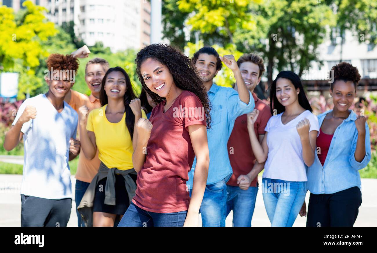 Jolie étudiante mexicaine avec groupe de jeunes adultes acclamant en plein air en été dans la ville Banque D'Images