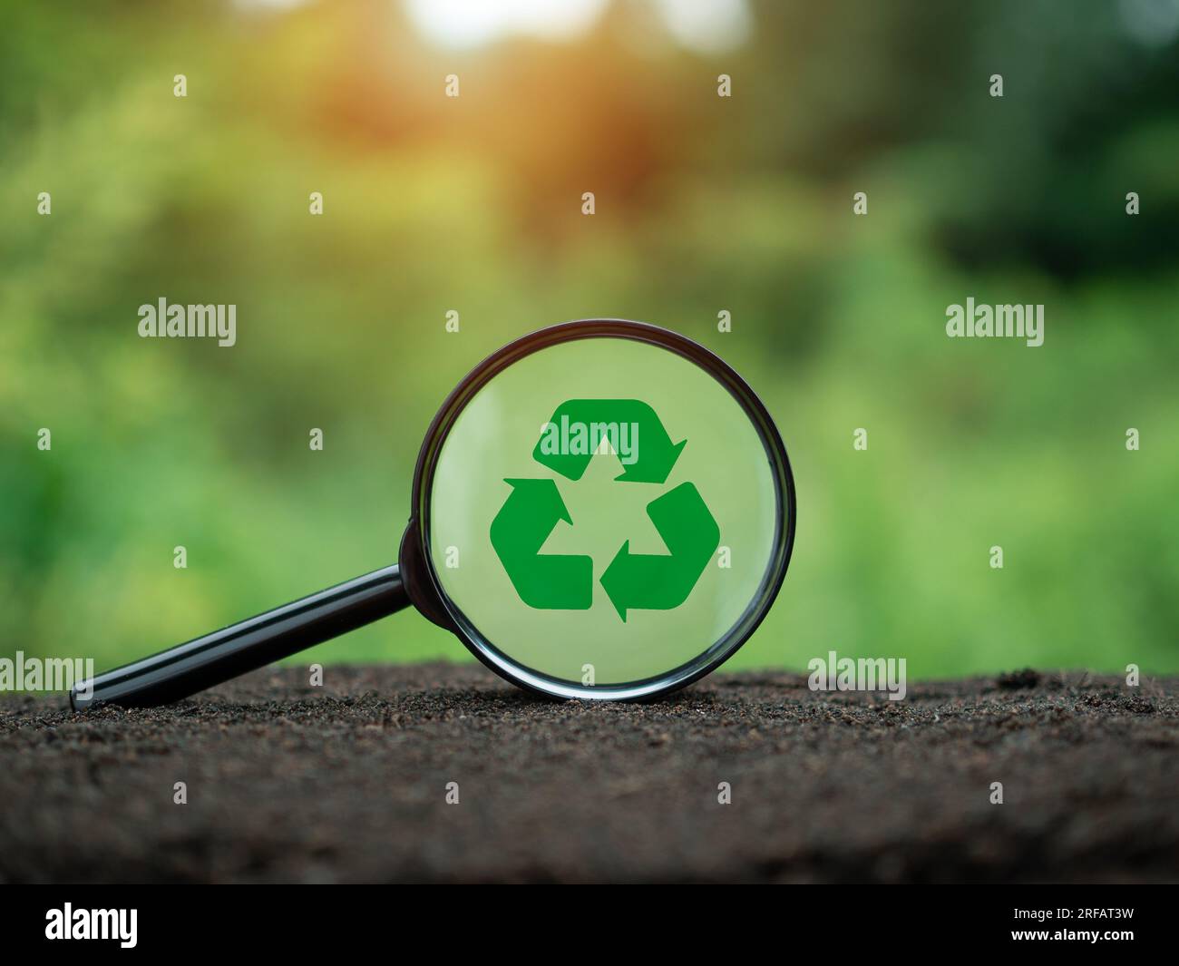 Concepts de réduction des déchets, pollution, réutilisation, utilisation efficace des ressources. Symbole de recyclage dans la loupe sur fond de nature. Banque D'Images