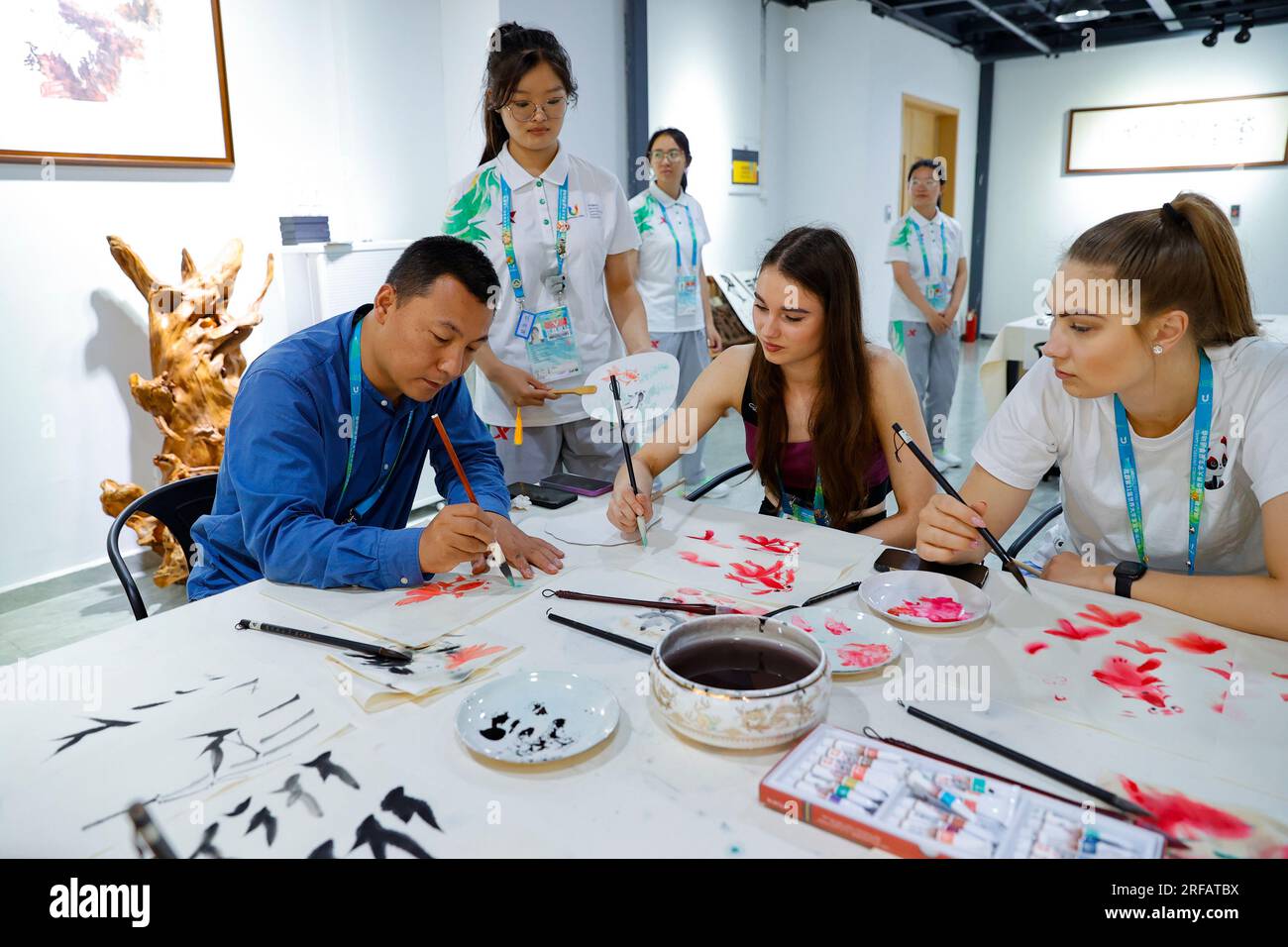 Chengdu, province chinoise du Sichuan. 31 juillet 2023. Jiao Hailong (1e L), professeur à l'Université normale du Sichuan, enseigne la peinture chinoise à Adelina Beljajeva (C) et Hanna Grete Vutt d'Estonie au Village des 31e Jeux mondiaux universitaires d'été de la FISU à Chengdu, dans la province du Sichuan, dans le sud-ouest de la Chine, le 31 juillet 2023. Crédit : Shen Bohan/Xinhua/Alamy Live News Banque D'Images