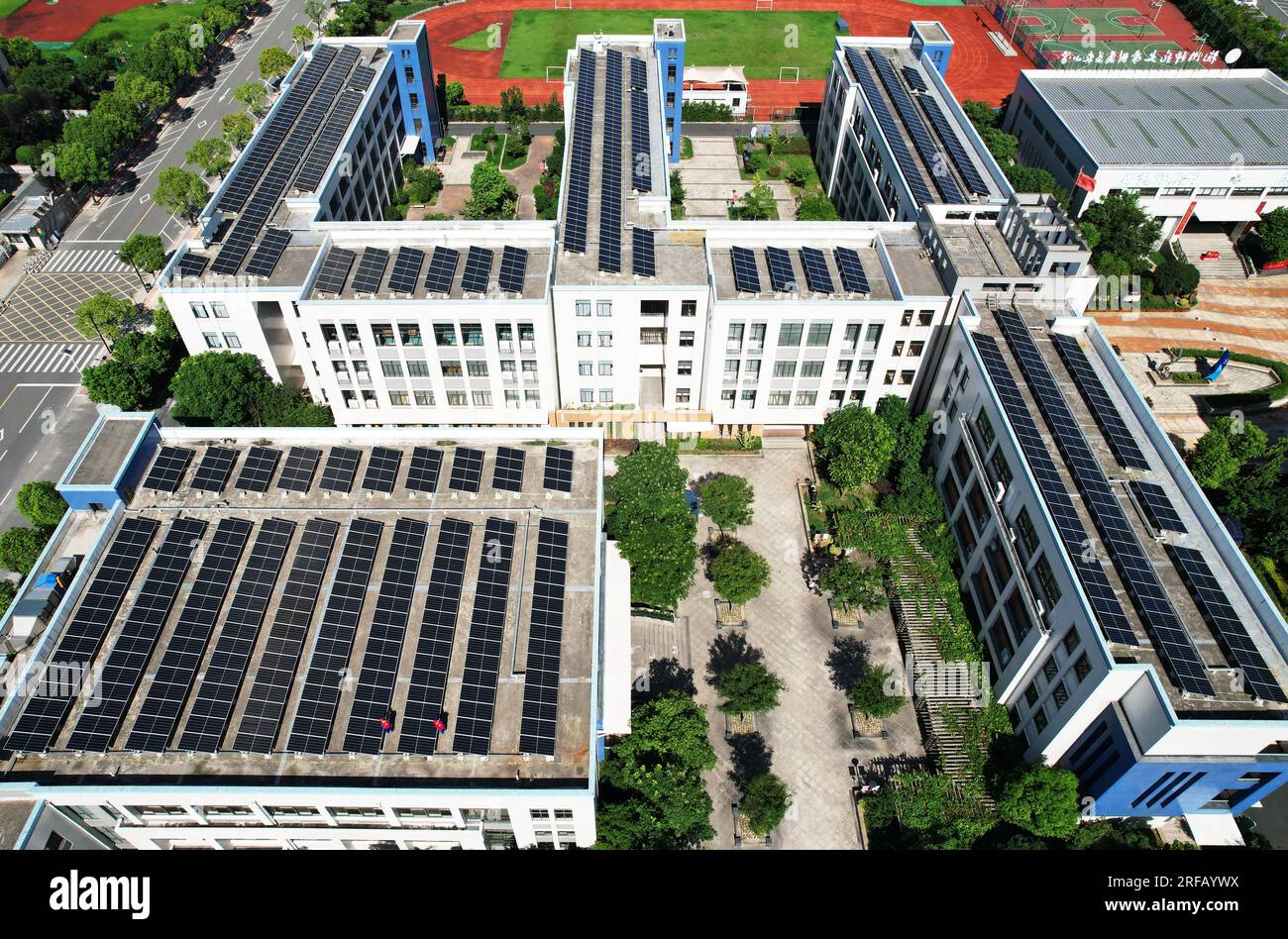 HANGZHOU, CHINE - 2 AOÛT 2023 - des employés d'une société d'alimentation électrique vérifient les installations de production d'énergie photovoltaïque sur le toit d'une école primaire Banque D'Images
