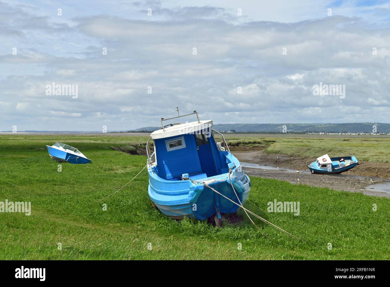 Il y a trois bateaux bleus tous amarrés sur le marécage par la zone étroite de la rivière juste à côté de Penclawdd au début de la péninsule de Gower. Banque D'Images