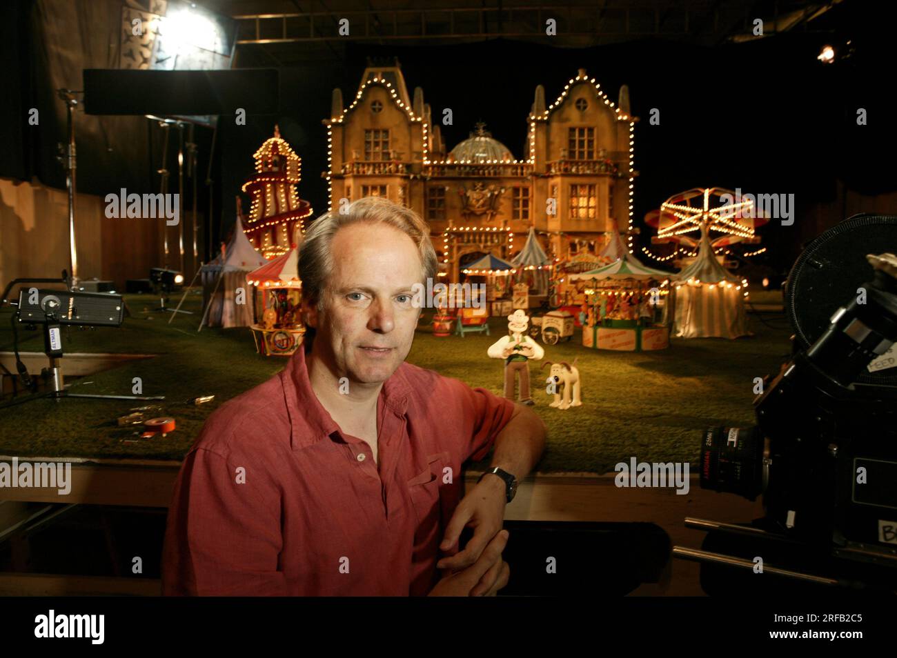 Portrait de Nick Park, créateur de personnages animés 'Wallace et Grommit' photographié avec une toile de fond qui est une scène de son film, 'Wallace et Grommit, la malédiction du lapin' dans ses studios Aardman, Bristol, Royaume-Uni. Banque D'Images