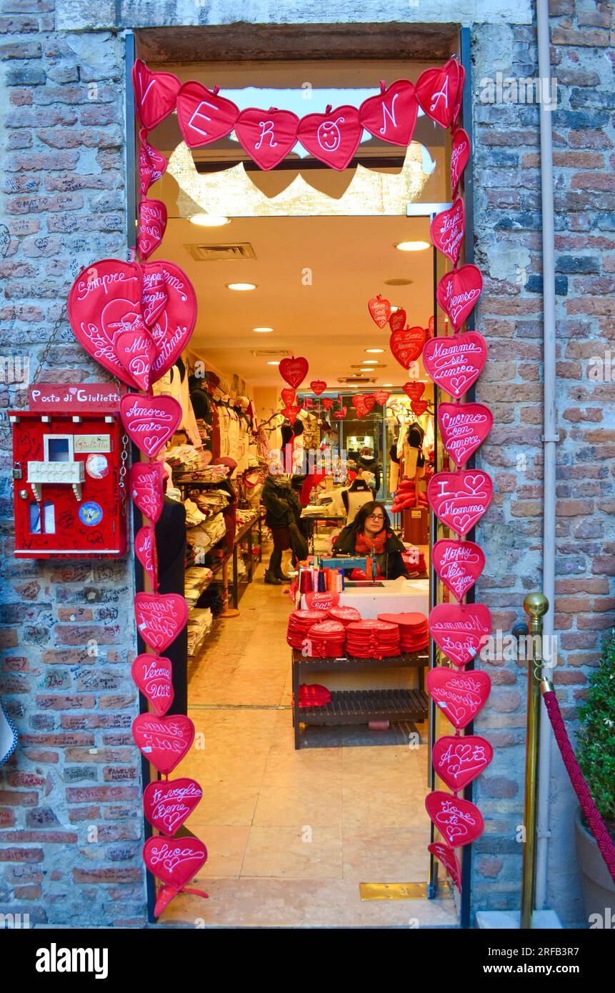 Vérone,Vénétie,Italie-9 février 2015:Décoration de coeurs rouges sur l'entrée de la boutique de cadeaux et femmes travaillant à l'intérieur dans le patio de la maison Juliette à Vérone Banque D'Images