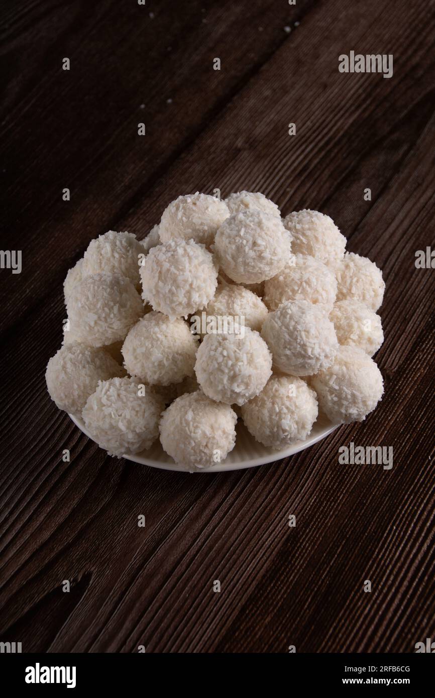 Photo de délicieux bonbons aromatisés à la noix de coco couchés sur une plaque blanche vue de dessus, nourriture sucrée, dessert Banque D'Images