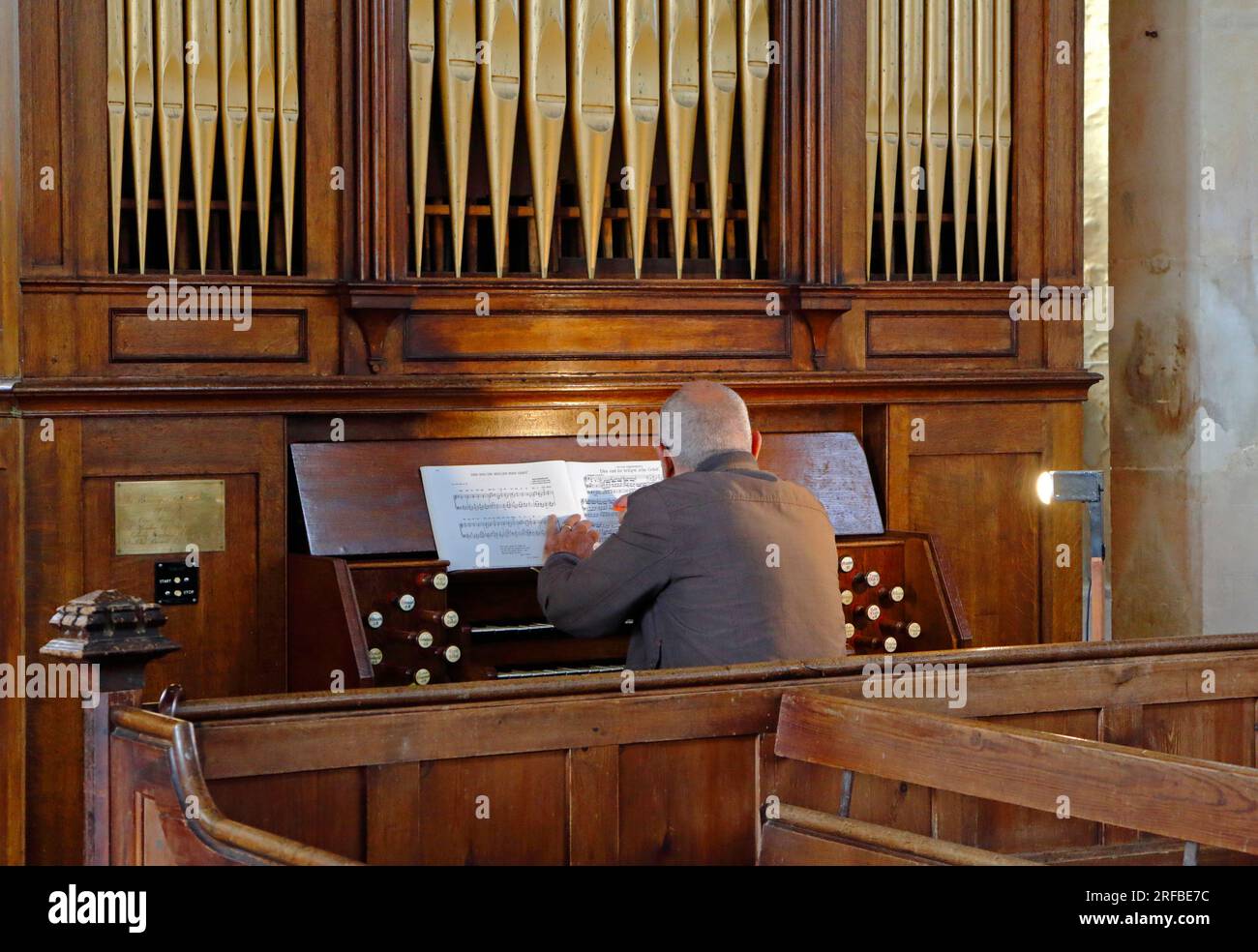 Organiste travaillant sur une partition musicale assis à l'orgue de l'église St Margaret à Cley Next the Sea, Norfolk, Angleterre, Royaume-Uni. Banque D'Images