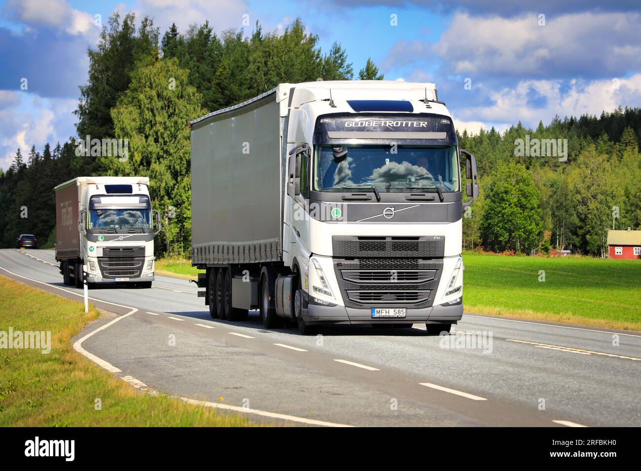 Deux semi-remorques Volvo FH blanches transportent des marchandises sur l'autoroute 2 un jour d'été. Jokioinen, Finlande. 21 juillet 2023. Banque D'Images