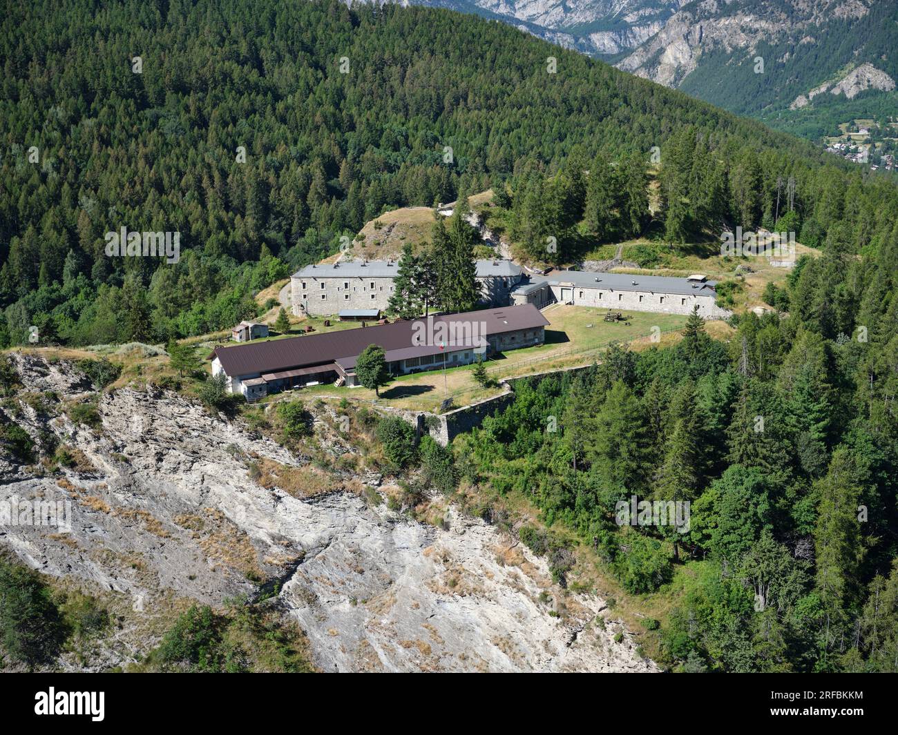 VUE AÉRIENNE. Fort de Bramafam, une fortification militaire sur une falaise surplombant la haute vallée de Susa. Bardonecchia, ville métropolitaine de Turin, Italie. Banque D'Images