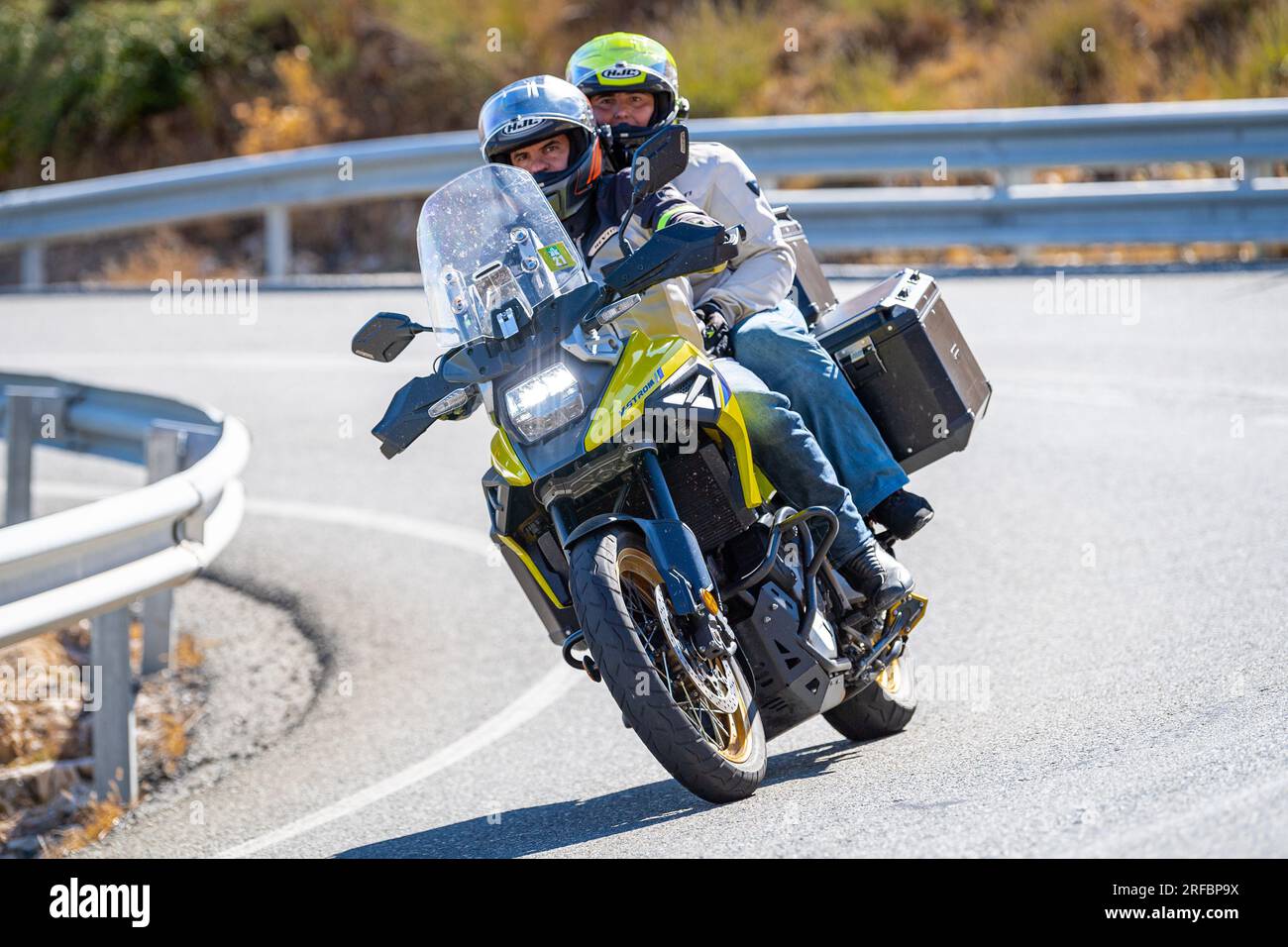 Pilote de moto prenant une courbe au premier plan, avec un fond de nature et de ciel bleu Banque D'Images