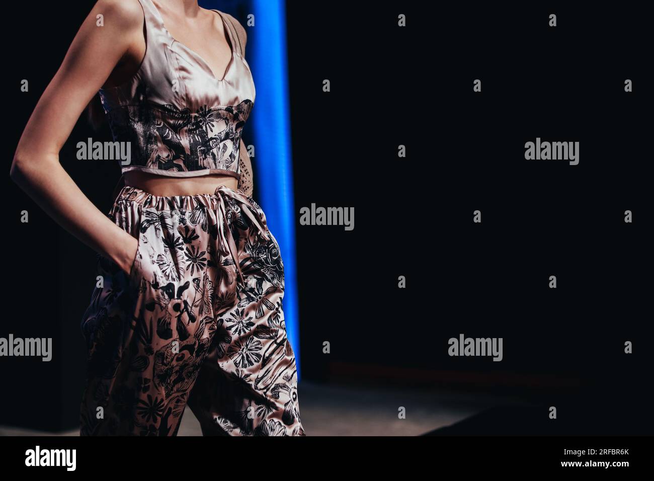 Figure de femme modèle de mode portant costume de designer de soie d'été avec ornement sur fond noir. Photo stylée et tendance. Tenue décontractée de style urbain Banque D'Images
