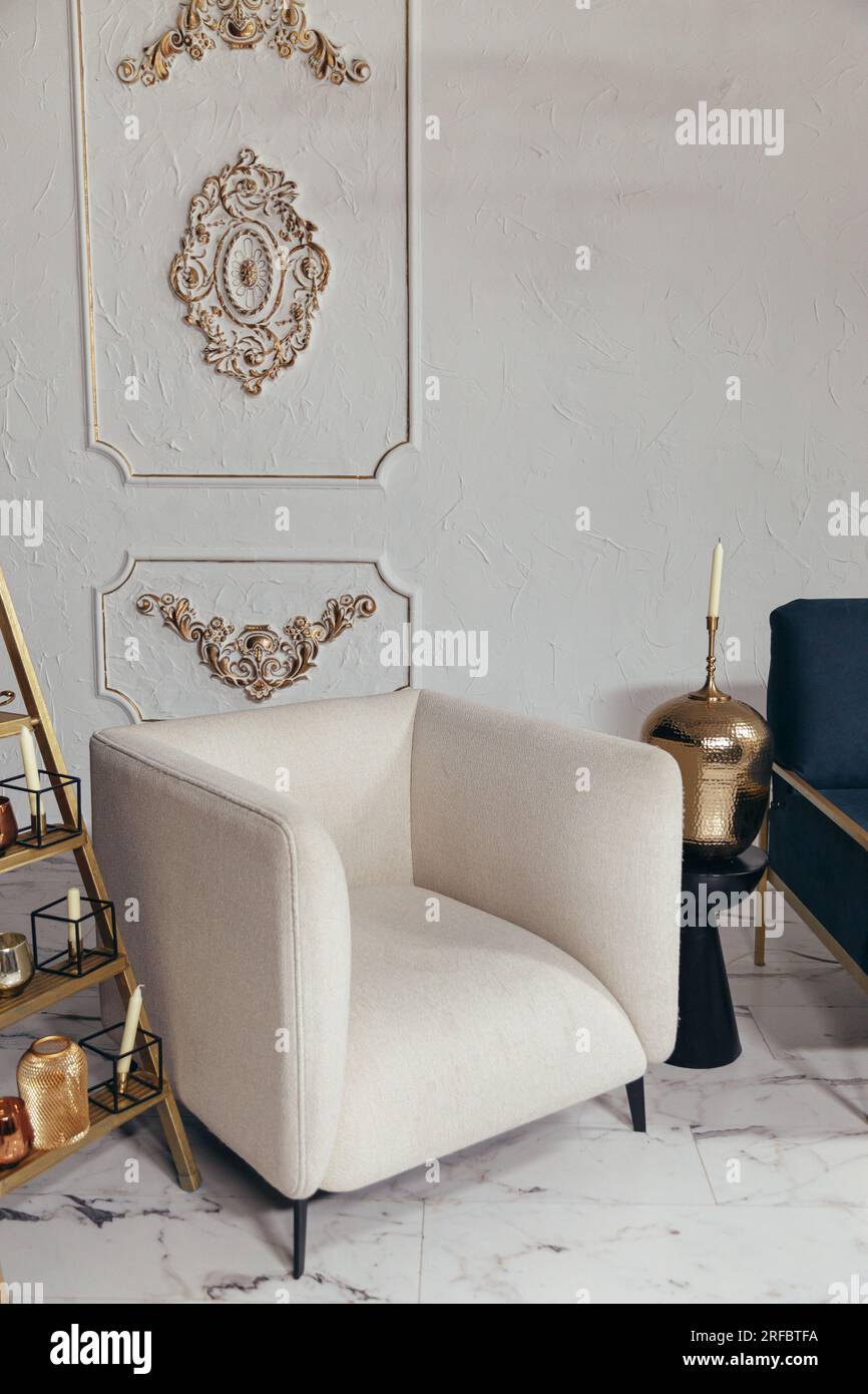 Gros plan d'une chaise souple beige dans un style classique. Chandelier en métal avec des bougies dans le salon avec un design intérieur élégant Banque D'Images