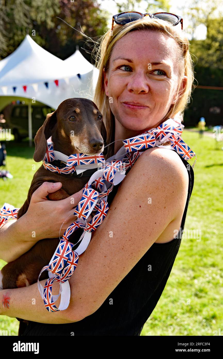 Jeune femme avec son chien lors des célébrations pour le couronnement du roi Charles, Alton, Hampshire, Royaume-Uni. Banque D'Images