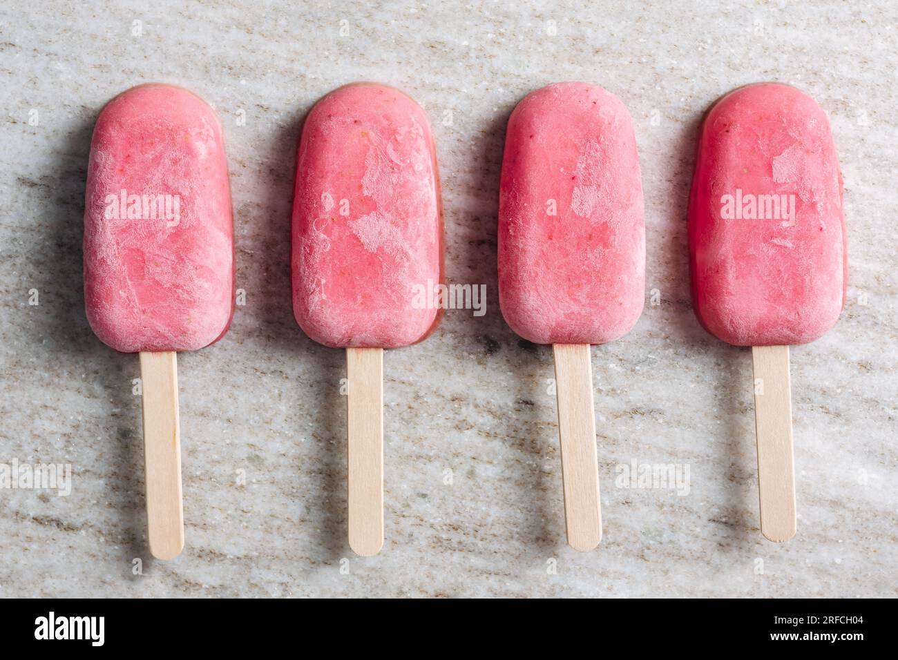 Des pop-glaces au yaourt à la fraise sur fond de marbre beige. Banque D'Images