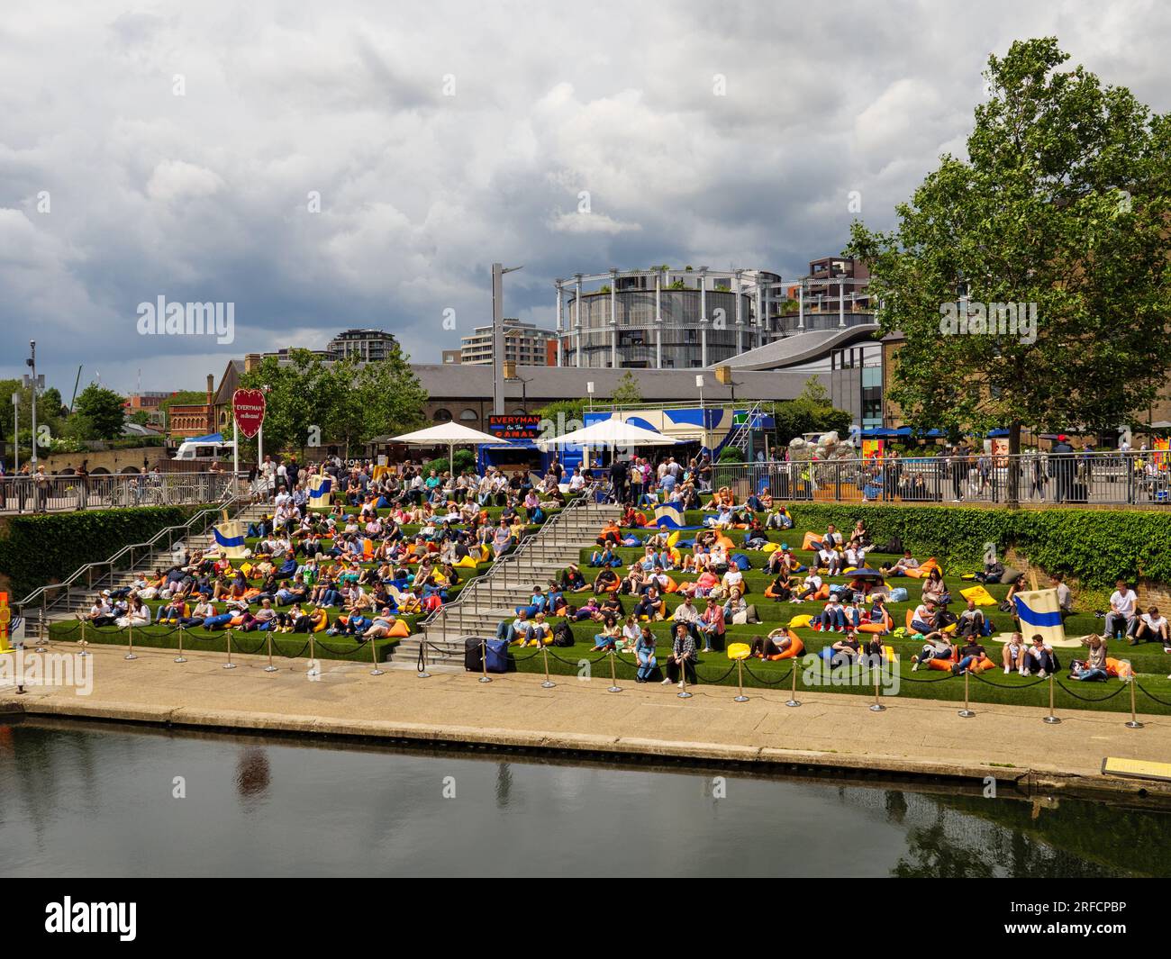 Les gens assis sur les marches au bord du canal de Granary Square à côté du Regent's Canal, Londres, Royaume-Uni Banque D'Images