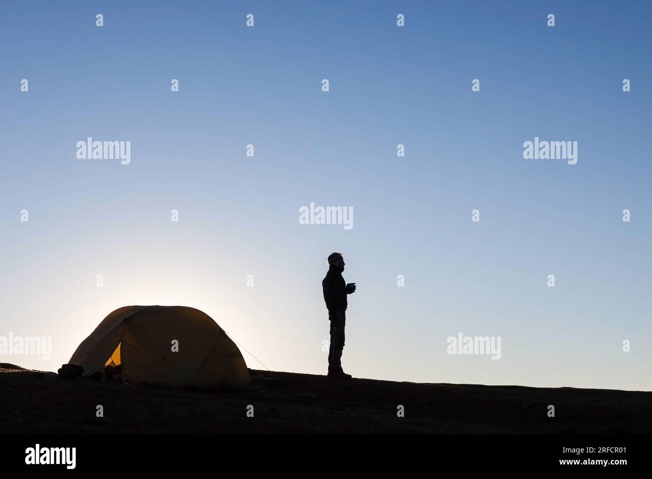 Silhouette de camping d'une tente et d'une fille dans les hautes montagnes de l'Himalaya au Népal. Voyageur seul debout près de la tente de camping regardant à la distance. Banque D'Images