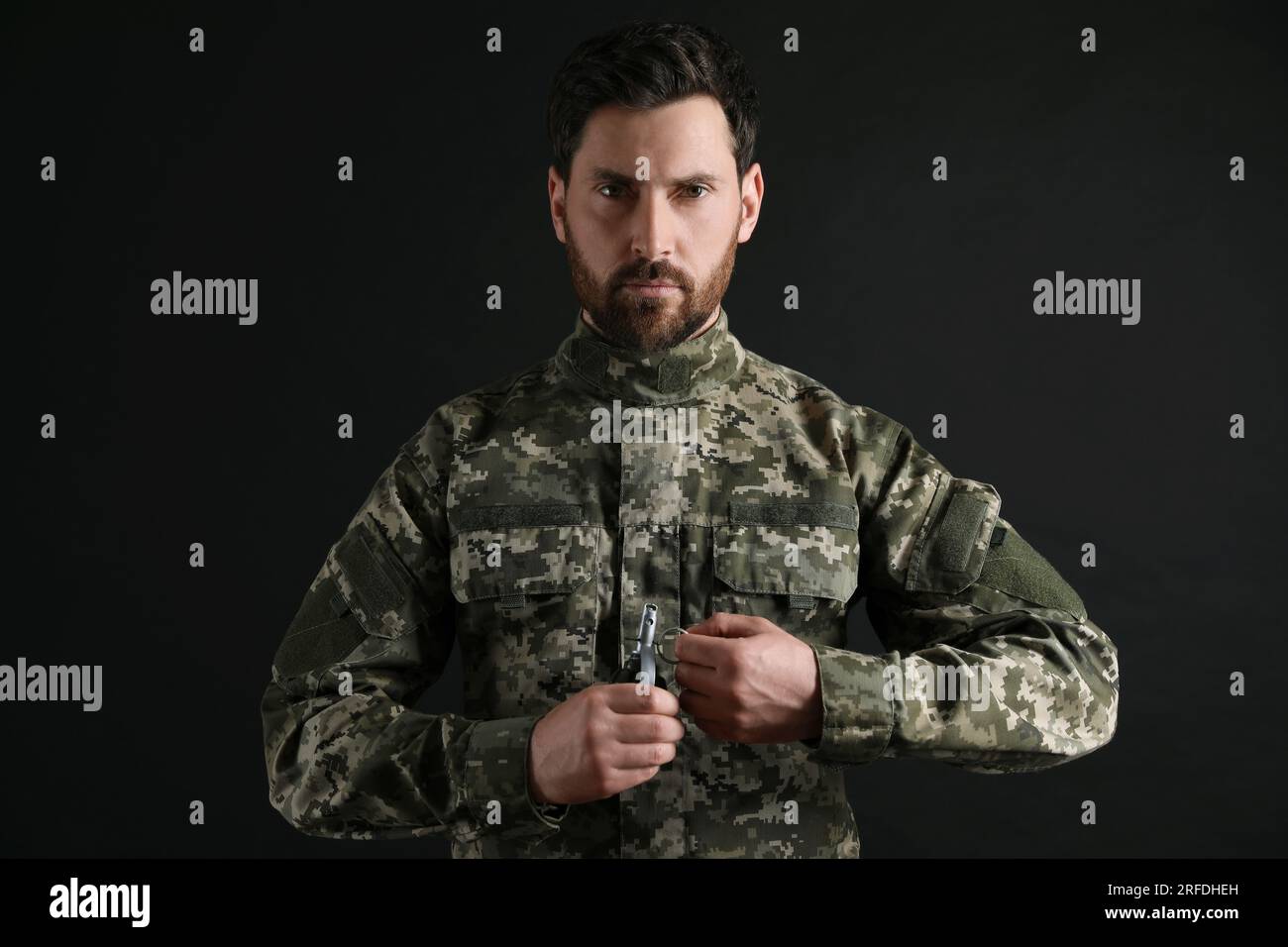 Soldat tirant l'épingle de sécurité hors de la grenade à main sur fond noir. Service militaire Banque D'Images