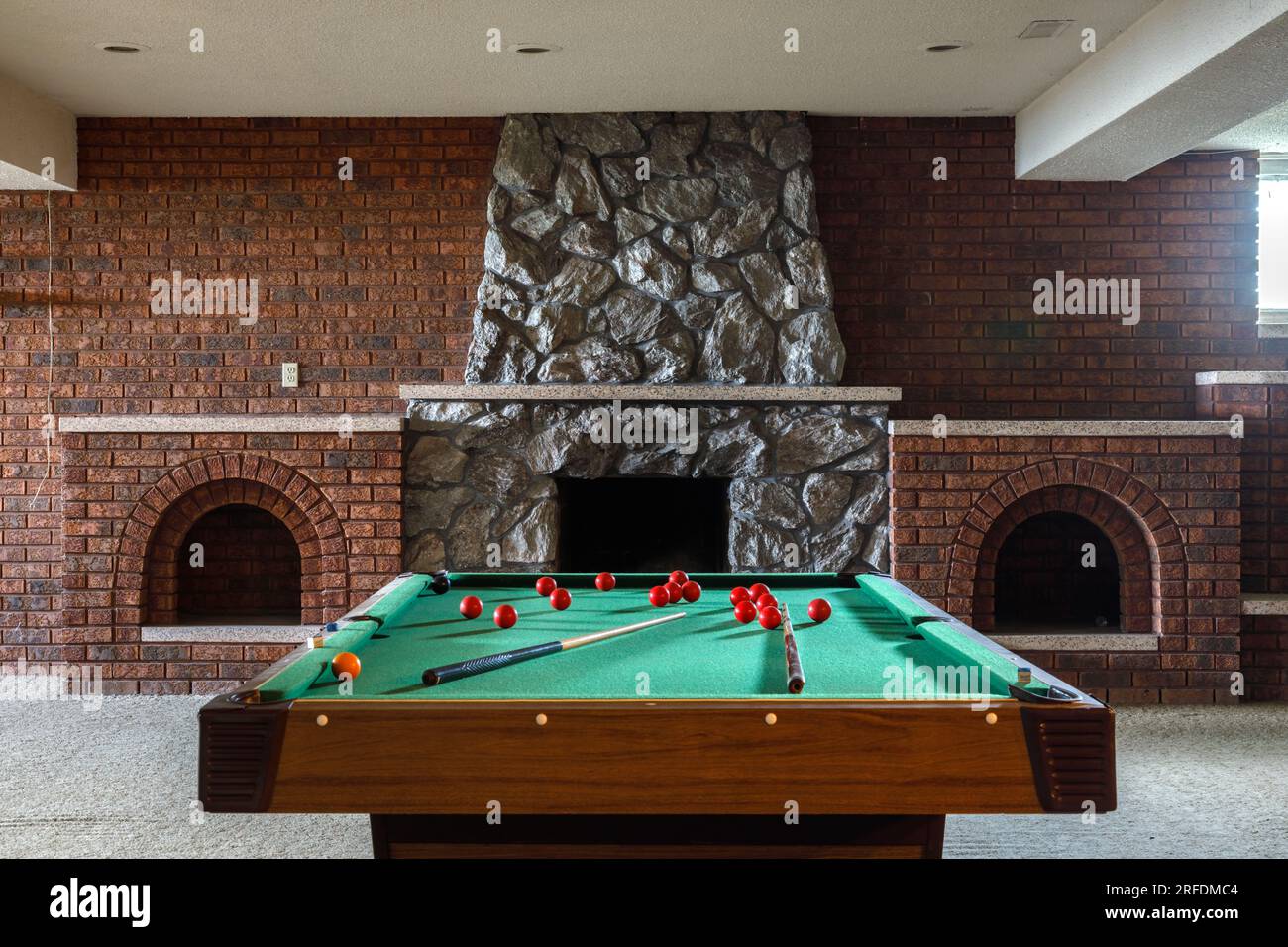 Une table de billard à l'intérieur d'une salle de loisirs au sous-sol avec une cheminée en pierre. Banque D'Images