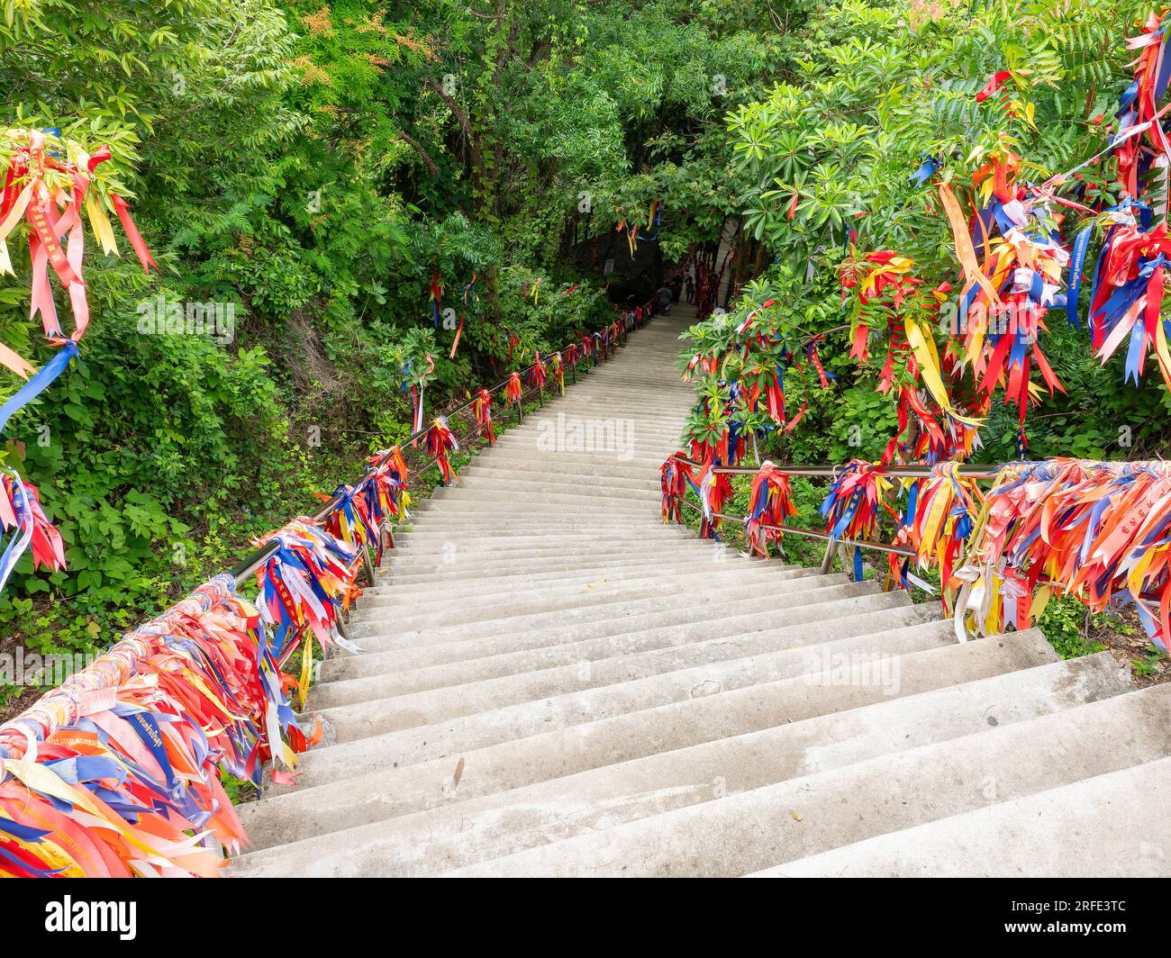 Escalier menant du sanctuaire au sommet de la colline à Wat Khao Tabaek à Chonburi, Thaïlande. Les balustrades sont décorées de rubans colorés que les visiteurs Banque D'Images
