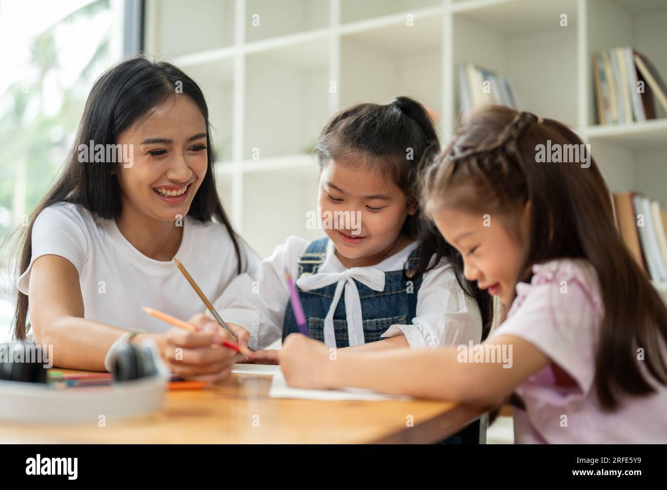Un professeur ou un professeur privé féminin asiatique de genre enseigne aux jeunes étudiants à la maison. maternelle, élèves de l'école primaire, enfants, garde d'enfants, enseignant Banque D'Images