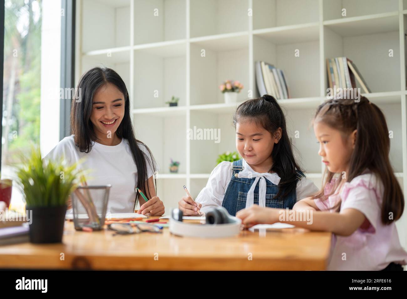Une enseignante privée asiatique amicale et gentille enseigne l'art aux jeunes étudiants à la maison. Enfants de maternelle, élèves de l'école primaire, enfants, bébé Banque D'Images