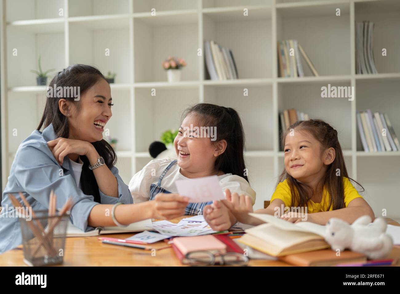 Deux adorables jeunes filles asiatiques rient et aiment étudier les cartes-éclair de l'alphabet anglais avec un professeur privé à la maison. préscolaire, maternelle, Banque D'Images