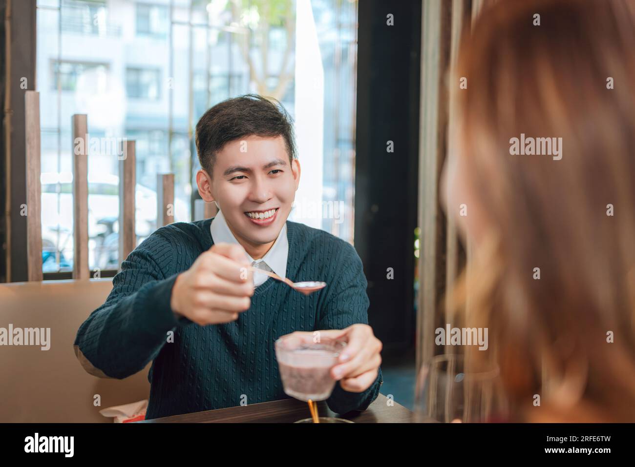 Jeune homme asiatique nourrissant la petite amie heureuse avec de la nourriture savoureuse dans le restaurant Banque D'Images