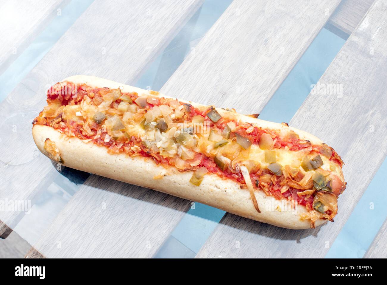 Hot Dog : un délicieux hot dog rempli de cornichons savoureux, d'oignons frits et d'un soupçon de sauce tomate, capturé dans une photo alléchante d'en haut sur un g. Banque D'Images