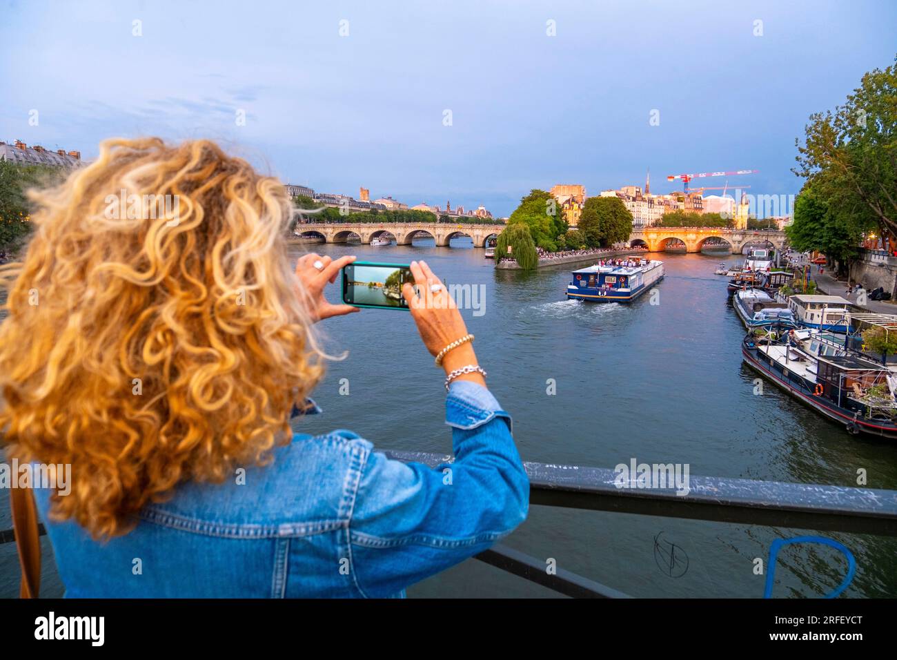 France, Paris, les bords de Seine classés à l'UNESCO, passerelle des Arts, touriste féminine photographiant l'Ile de la Cité Banque D'Images