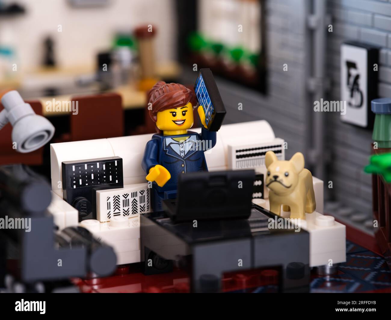 Tambov, Fédération de Russie - 02 juillet 2023 Une minifigurine Lego travaillant à la maison, répondant à un appel téléphonique. Un chien bulldog français assis sur un Banque D'Images